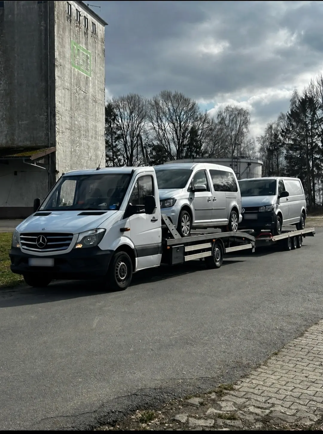 Abschleppwagen mit zwei Vans auf Ladefläche und Anhänger